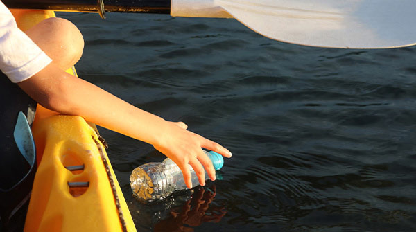 persona raccoglie bottiglia dal mare